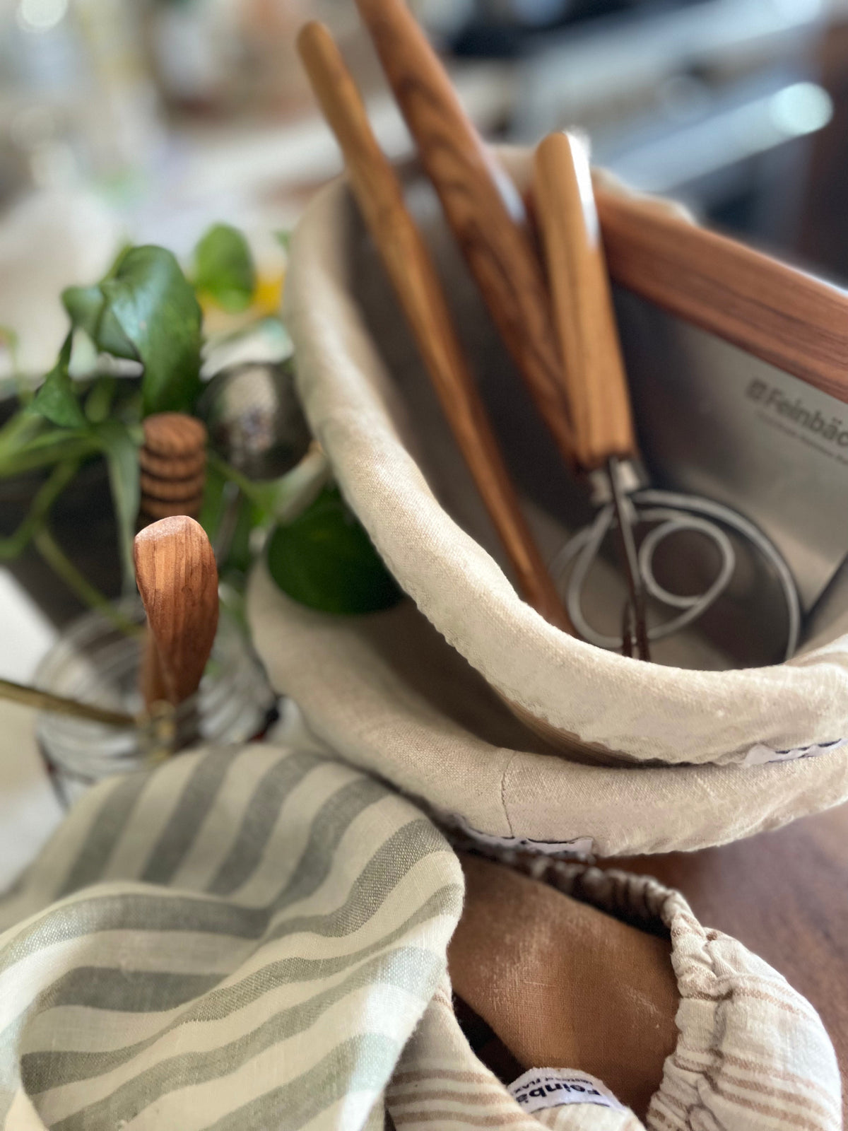 Shown are the essential Sourdough tools. Presented are 2 bannetons, a bench scraper, a danish dough whisk, an olive wood spurtle, linen bowl covers to cover dough. Also shown in picture is an olive wood butter knife and olive wood handled lame 